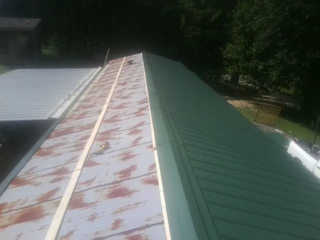 Old rusted panels beside newly installed green metal roofing — Wind Damage Roof Repair by Roofing Brothers in Hopewell Junction