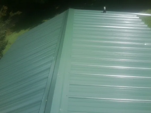 New green metal panels meeting at the ridge of a roof — Flat Roof Repair work by our crew in Hopewell Junction