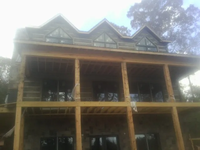 Dormers and porch framing on a large log home under construction — Roof Coating work by our crew in Hopewell Junction