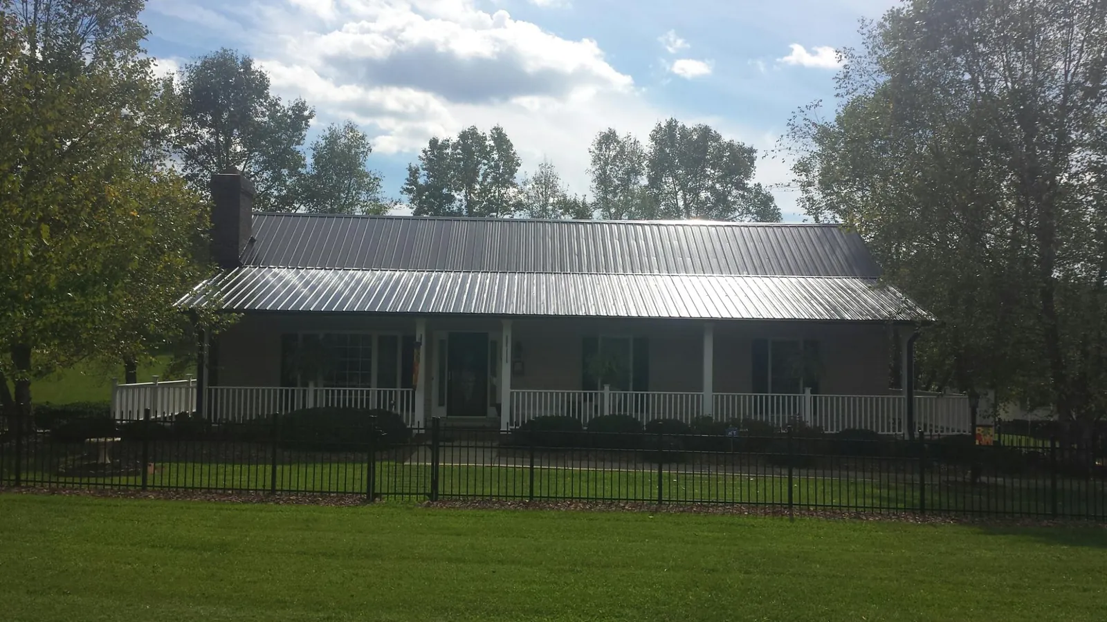 Gray metal roof on a brick ranch with a full width front porch — Gutter Guard Installation work by our crew in Hopewell Junction