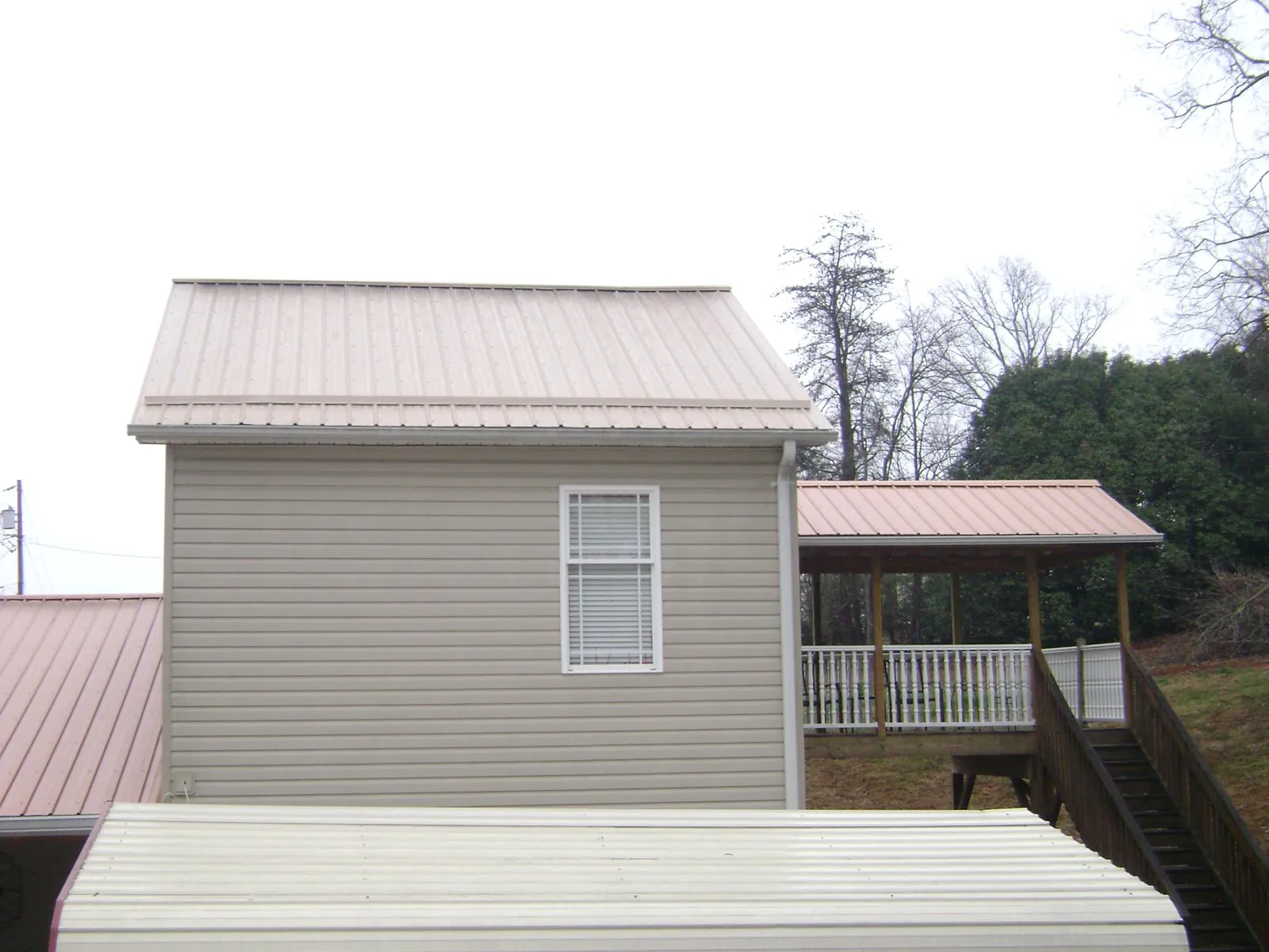 Tan metal roofs on a two story addition and attached porch, from a Roof Replacement job in Hopewell Junction