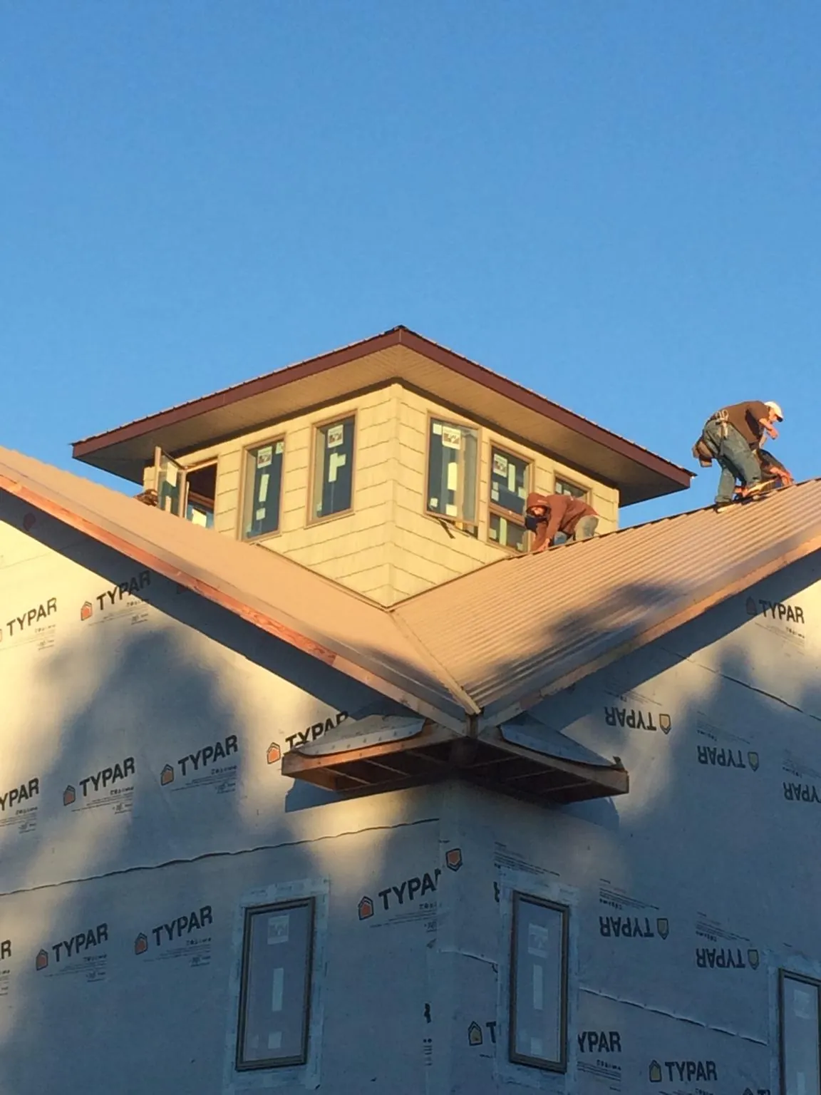 Roofers working around a rooftop cupola on a new metal roof at sunset — Roof Waterproofing in Hopewell Junction by Roofing Brothers